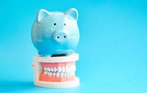 blue piggy bank sitting on top of a set of dentures