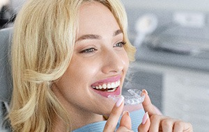 Patient smiling while holding clear aligner