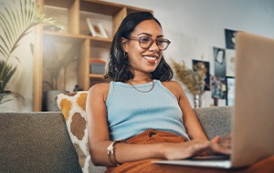 Woman smiling while working on laptop at home