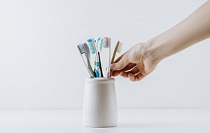 Hand reaches for toothbrush in holder