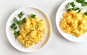 Two plates with scrambled eggs and garnish