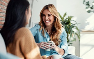 Woman smiling while drinking coffee with friend