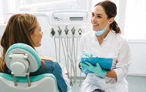 Dentist smiling while taking notes on clipboard