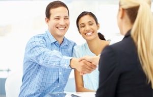 Couple shaking hands with dentist at dental implant consultation