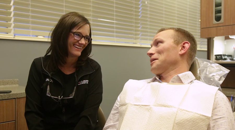 Man in dental chair laughing with dental team member in Lincoln