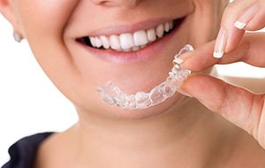 Closeup of smiling patient holding Invisalign tray