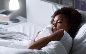 Woman resting in bed with white sheets and blanket