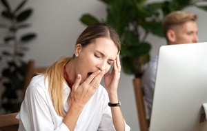 Woman feeling tired at her desk during work