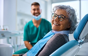 Woman with glasses smiling in treatment chair