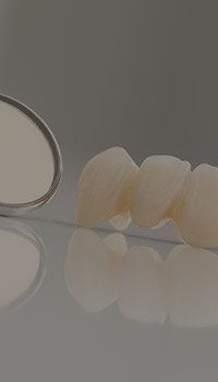 Fixed dental bridge on table next to dental mirror