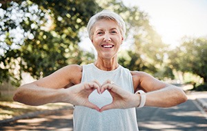 Lady smiles while making shape of heart with her hands