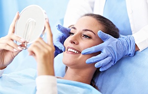 Female dental patient checking teeth in mirror