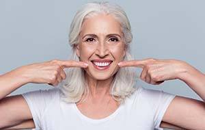 older woman pointing to her smile