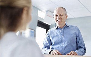 Man discussing dental insurance at reception desk