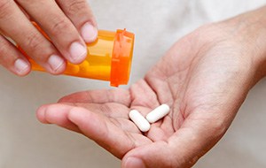 Hand holding two white antibiotic tablets