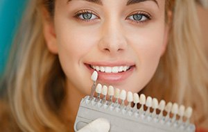 Woman's smile compared with tooth color chart