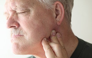 Man holding jaw in pain needs a root canal