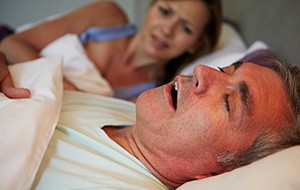 Frustrated woman looking at snoring man in need of sleep apnea therapy