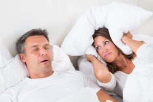 A woman closing her ears because her husband snores