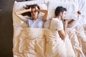 man snoring while woman upset lies awake