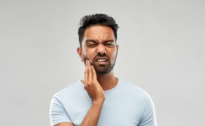 Man holding jaw in discomfort