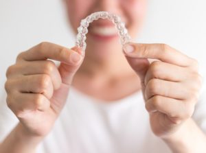 Smiling woman holding clear braces