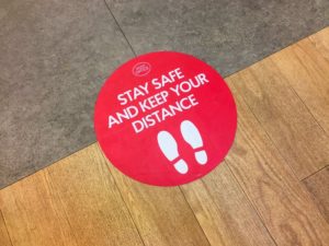 Red floor sign from Lincoln dentist encouraging social distancing in COVID-19