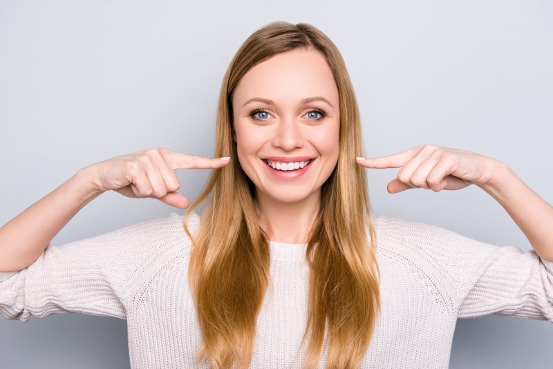 Woman pointing to her aesthetically pleasing smile