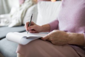 mature woman writing on notepad