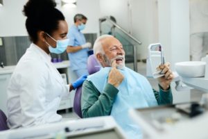 mature man looking at teeth in mirror