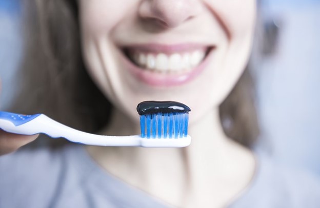 Woman using activated charcoal on her toothbrush.