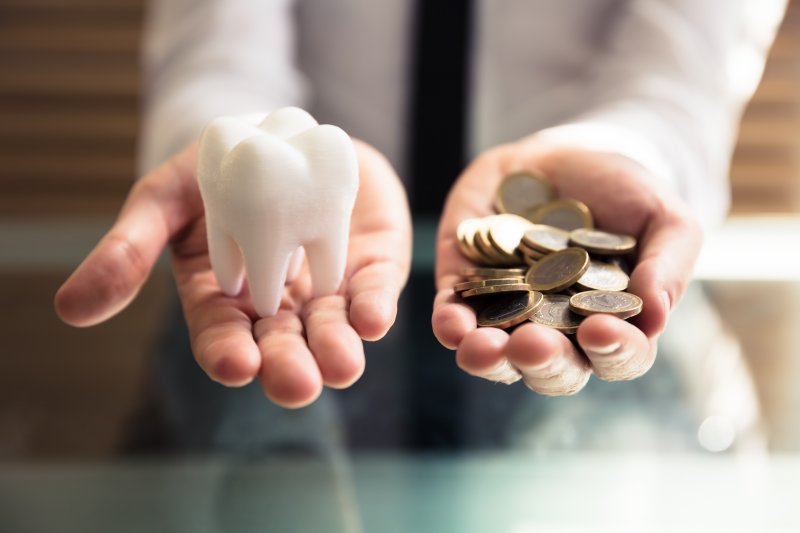 A dentist in Lincoln holding a white tooth and gold coins