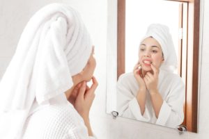 Woman inspecting her teeth in the bathroom mirror.