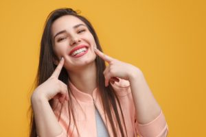 Smiling woman pointing to her smile