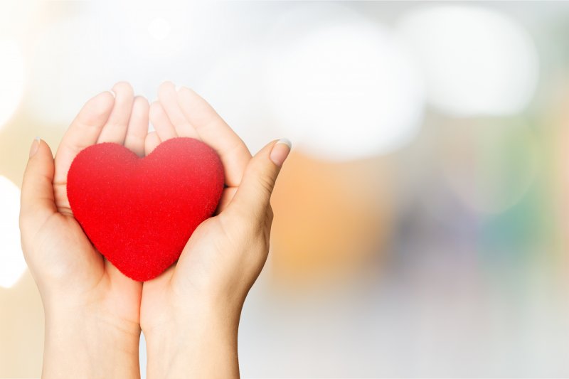 Hands holding a heart made of felt fabric