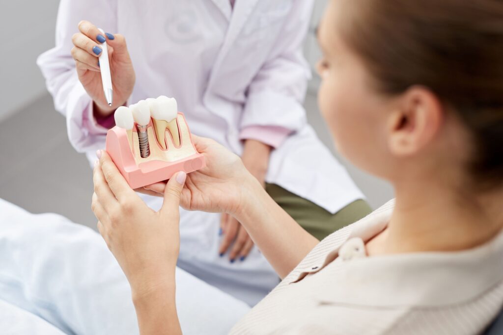 Patient holding sample implant as dentist points to it