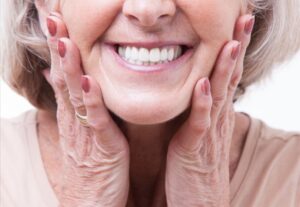 Older woman smiling and showing off dentures.