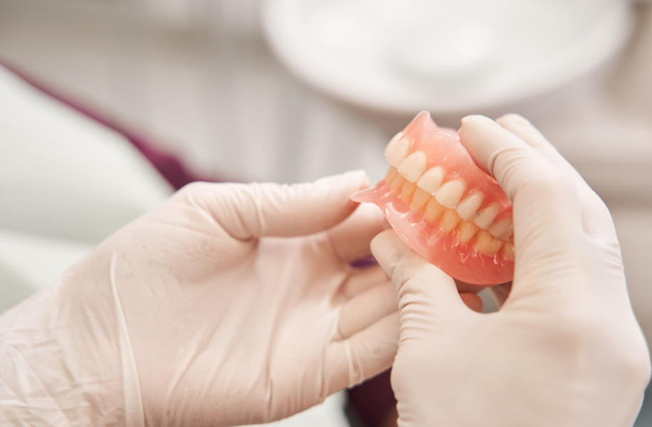 Gloved hands holding dentures